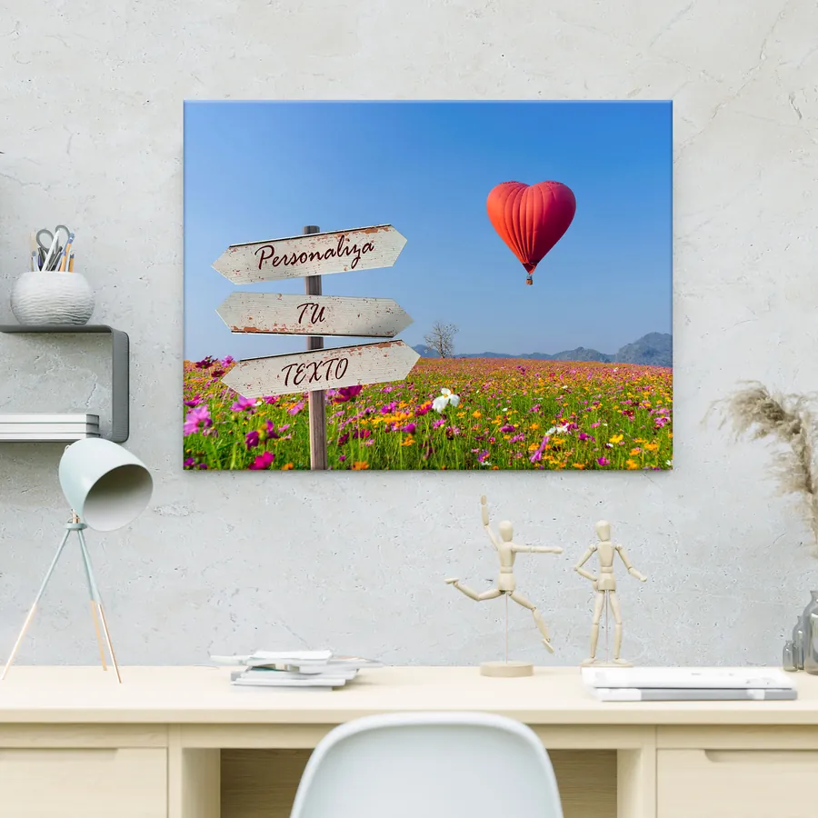 Cuadro con texto personalizado colgado en la pared: globo en forma de corazón y campo de flores con cartel para tu frase