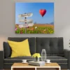 Cuadro con texto personalizado colgado en la pared: globo en forma de corazón y campo de flores con cartel para tu frase