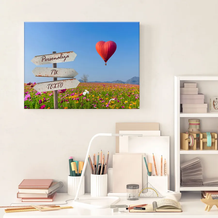 Cuadro con texto personalizado colgado en la pared: globo en forma de corazón y campo de flores con cartel para tu frase